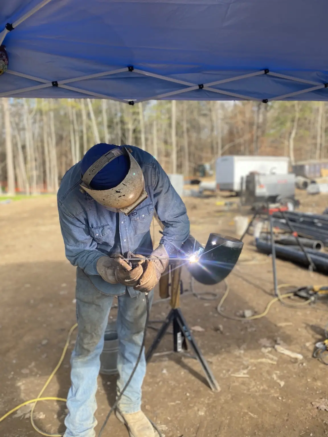 Field welding steel outdoors beneath a work canopy